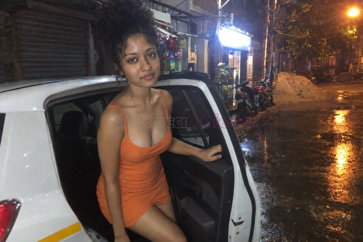 Call girl in Kolkata getting out of a car on a wet street at night