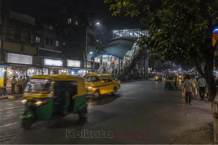 A main road in Tollygunge, Kolkata, at night with autos and a yellow taxi