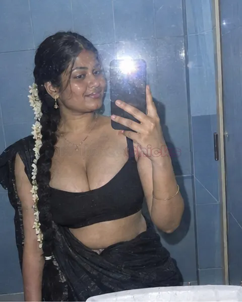 South Indian escort with jasmine in her hair taking a bathroom mirror selfie