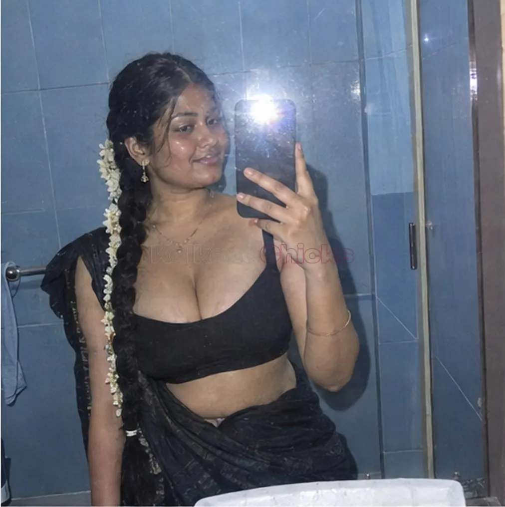 South Indian escort with jasmine in her hair taking a bathroom mirror selfie