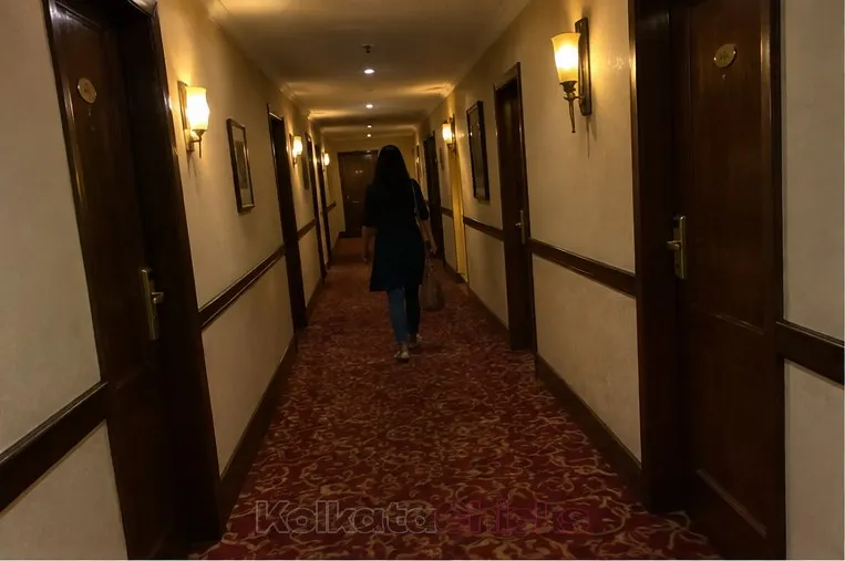A woman walking down a quiet hotel corridor in Kolkata at night