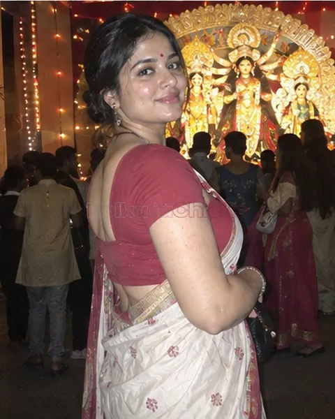 Bengali escort in a red blouse and saree at a Durga Puja pandal at night