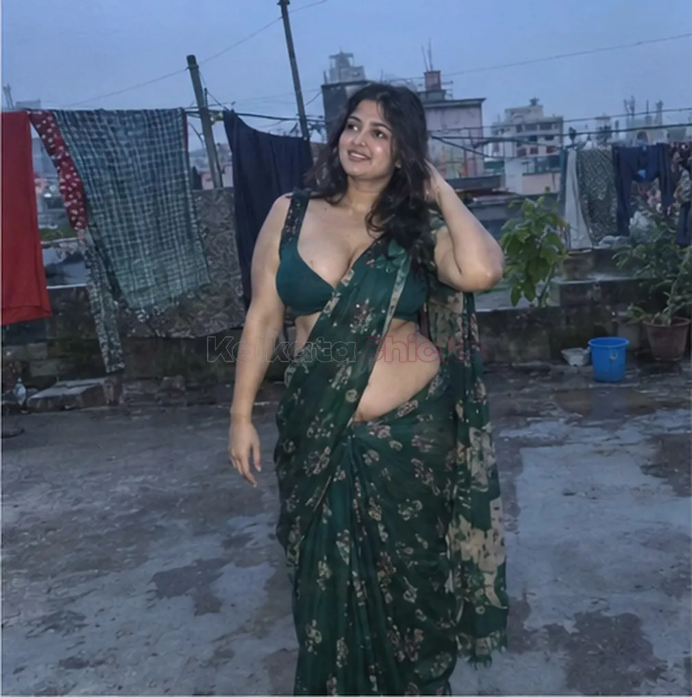 Curvy escort in Kolkata in a green saree on a rooftop at dusk