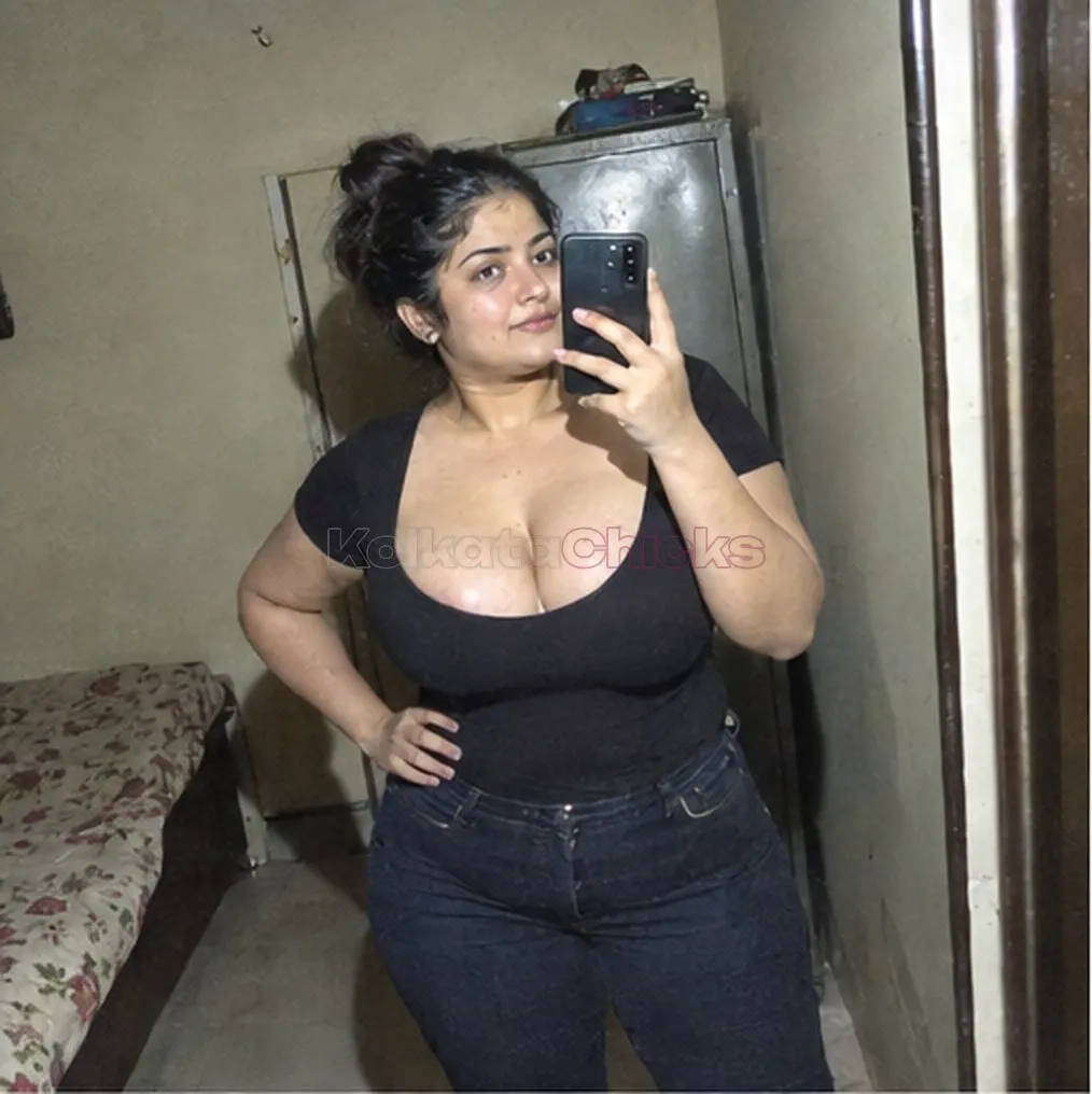 Busty Kolkata escort in a black top taking a mirror selfie in her room