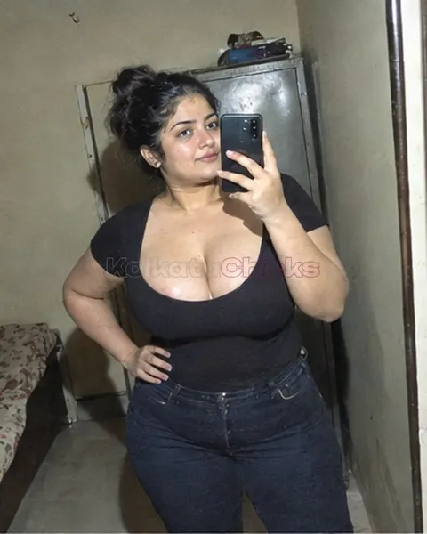 Busty Kolkata escort in a black top taking a mirror selfie in her room