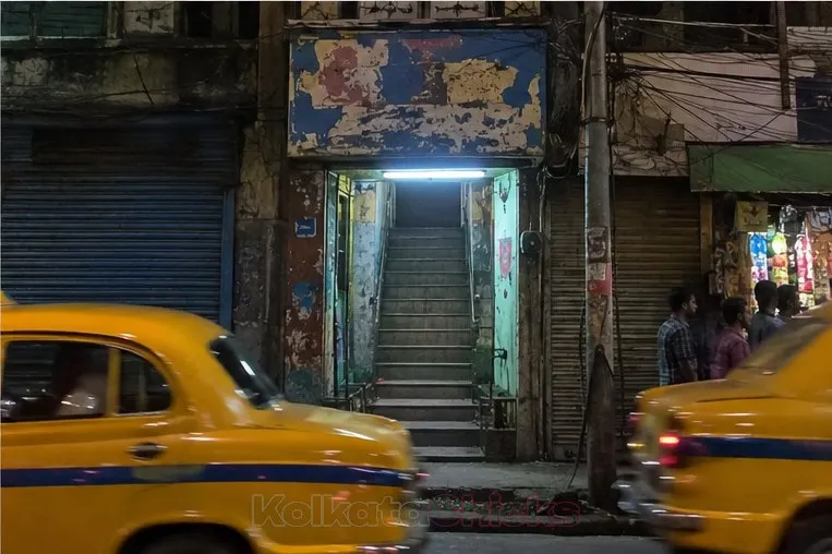 The stairs of a cheap lodge near a Kolkata railway station, with yellow taxis passing