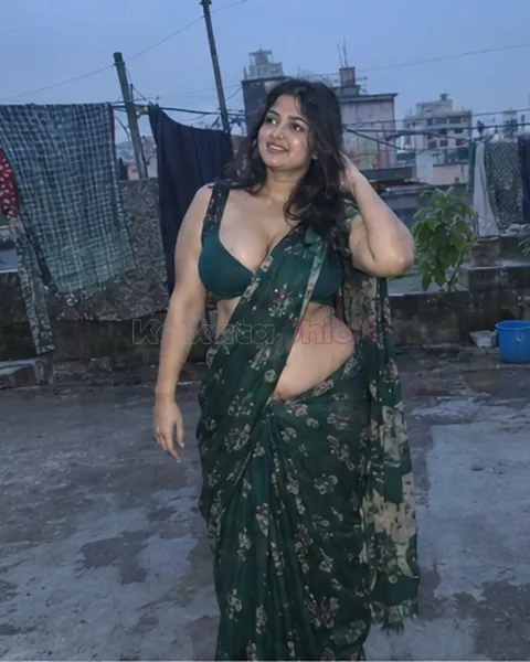 Curvy escort in Kolkata in a green saree on a rooftop at dusk