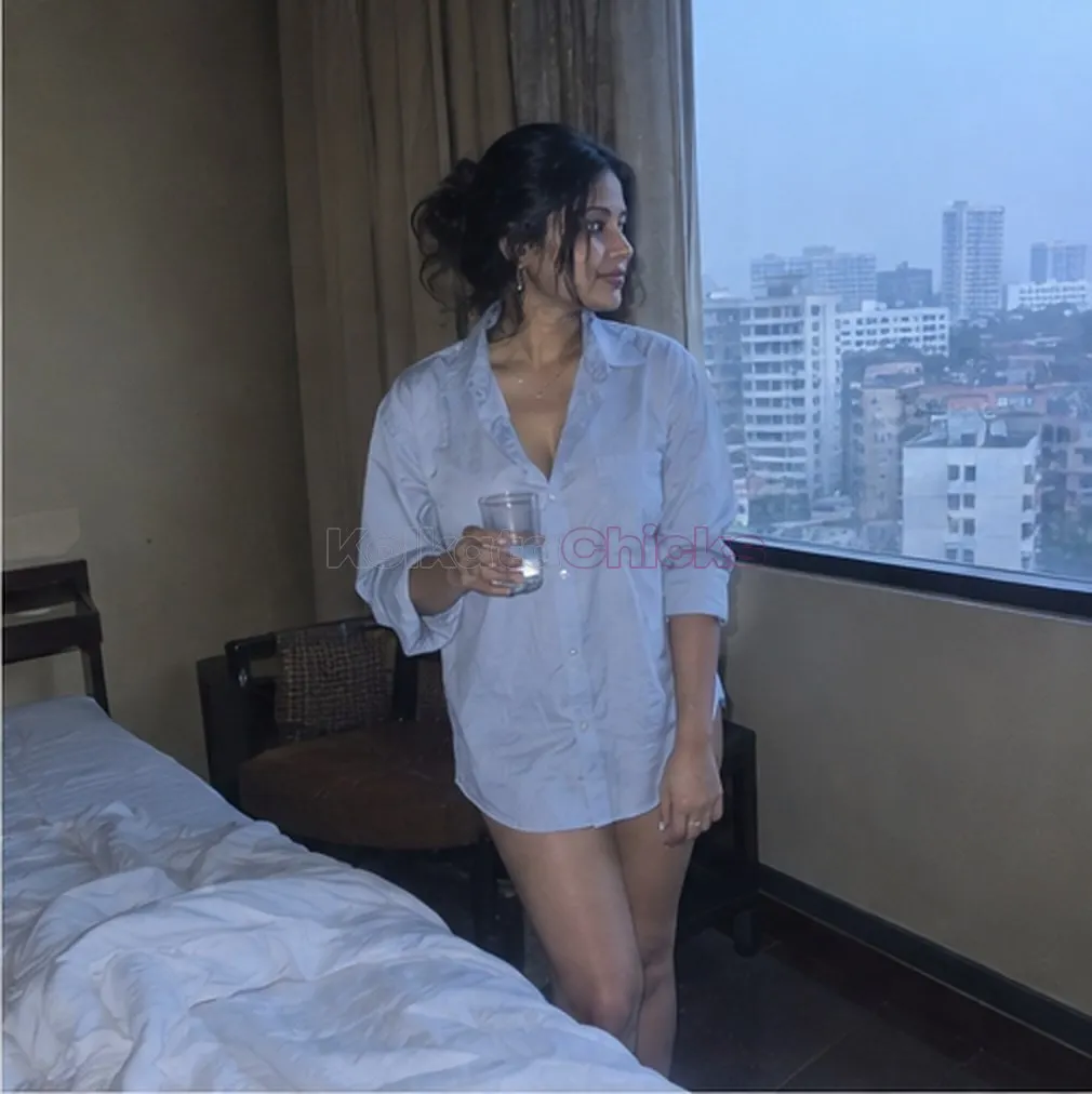 Kolkata escort in a white shirt at a hotel window in the morning